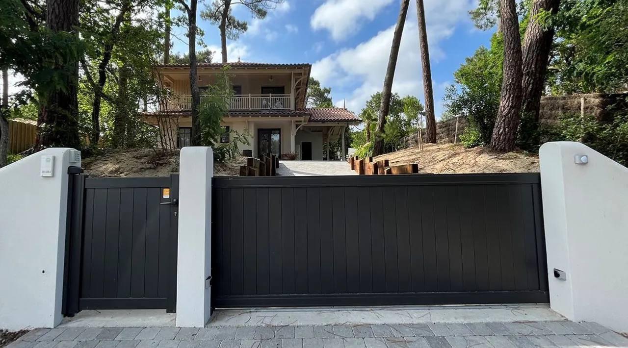 Portail coulissant aluminium anthracite et portillon devant une maison